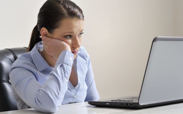 Latin woman looking disappointed at her laptopscreen, sitting behind her desk at the office.