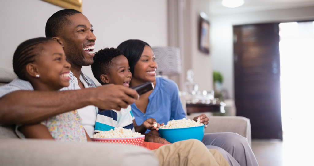 Cheerful family having popcorn while watching television at home