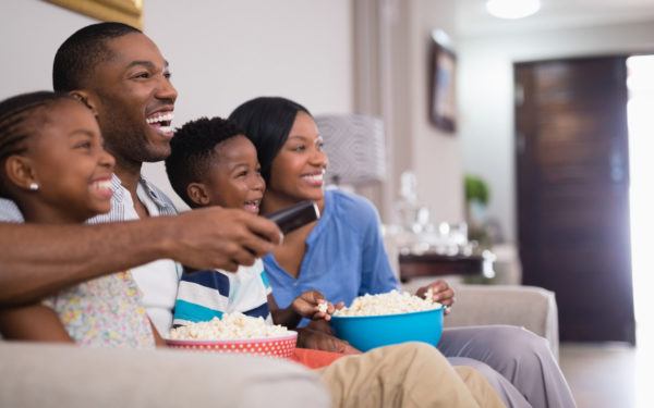 Cheerful family having popcorn while watching television at home