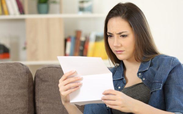 woman holding bill looking confused